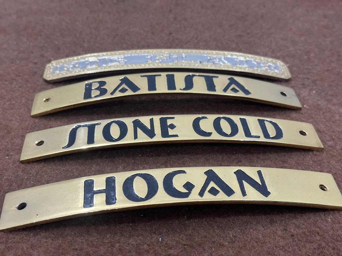 Four brass nameplates with engraved names on a brown background