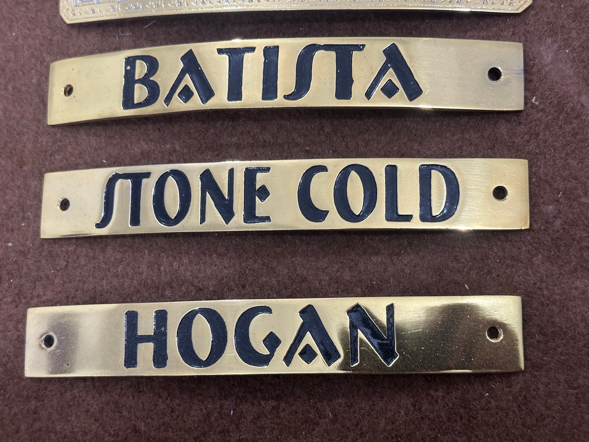 Brass nameplates with engraved names on a brown background